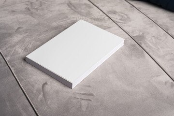 Book with blank cover on gray velvet sofa backdrop, editable mock-up series template