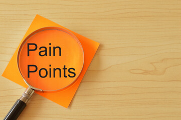 Magnifying glass and orange paper with text PAIN POINTS.
