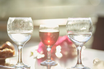 Glass of red wine and glasses of water on the table. Decorations of pink bougainvillea flowers.