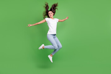 Fototapeta na wymiar Full length photo of crazy brunette millennial lady jump wear t-shirt jeans isolated on green color background