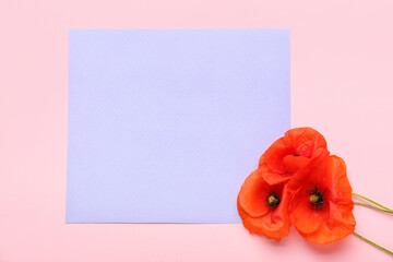 Beautiful red poppy flowers and paper sheet on color background
