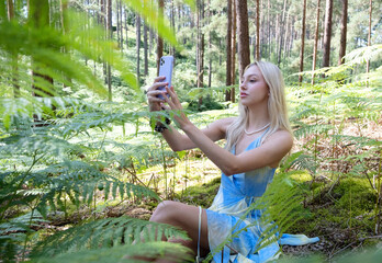 Beautiful woman doing a selfie on her phone in a forest