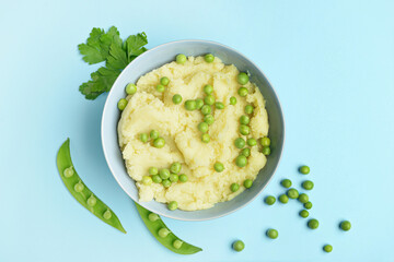 Bowl with mashed potatoes and green peas on color background