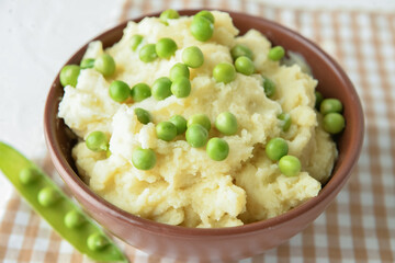 Bowl with mashed potatoes and green peas on table, closeup