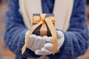 Female hands holding a gift box with a silk ribbon