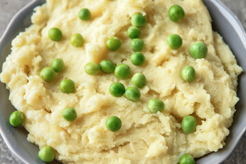 Bowl with mashed potatoes and green peas, closeup