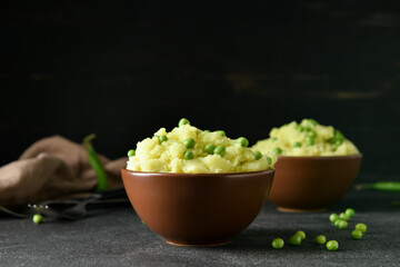 Bowls with mashed potatoes and green peas on table