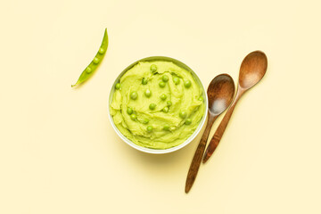 Bowl with mashed potatoes, green peas and spoons on color background