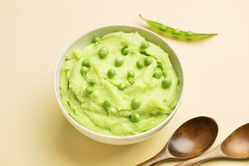 Bowl with mashed potatoes, green peas and spoons on color background