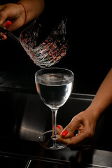 woman bartender holding tweezers with decoration of caramel and flower petals over glass with drink