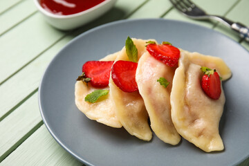 Plate with tasty strawberry dumplings on color wooden background, closeup