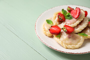 Plate with tasty strawberry dumplings on color wooden background, closeup