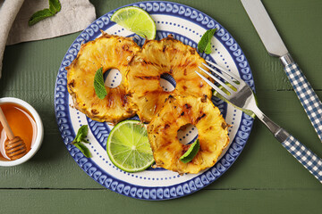 Plate with grilled pineapple slices, honey and lime on color wooden background