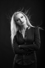 Elegant blond lady with perfect makeup and long straight hair wears blouse, posing at studio. Black and white sho