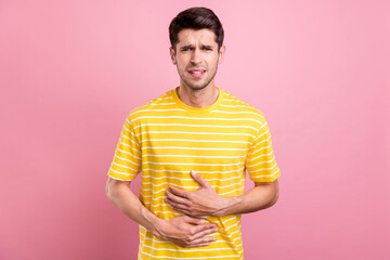 Portrait of attractive sick guy feeling bad touching belly tummy diagnosis isolated over pink pastel color background