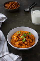 Thick pumpkin soup with baked chickpeas and radish sprouts in a plate with a glass of milk on the table, delicious healthy dinner