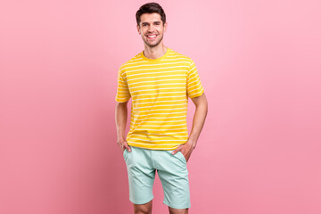 Photo of charming young happy man hold hands pockets good mood smile isolated on pink color...