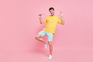 Fototapeta na wymiar Full length photo of cheerful young happy man dance hold hand glasses summer isolated on pink color background
