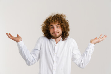 Young curly man with ginger hair holding and showing copyspace