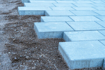 Gray rectangular paving slabs in the process of laying, top view