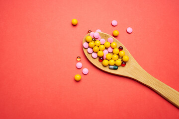 pills in a spoon on a red background top view antibiotics medicine