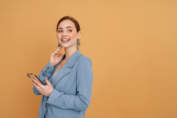 Young ginger woman laughing while using mobile phone