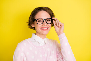 Photo of young attractive woman happy positive smile hand touch glasses isolated over yellow color background
