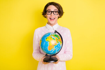 Photo portrait female student amazed holding globe at lesson in college isolated vivid yellow color background