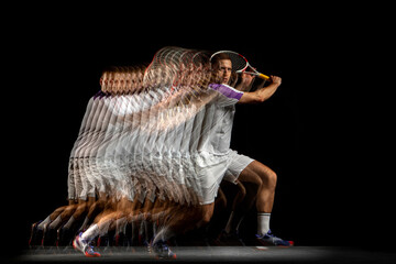 Power and speed. Young man, professional tennis player in motion and action isolated on dark...