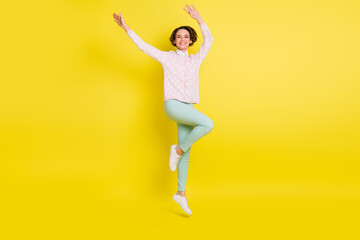 Fototapeta na wymiar Full length body size photo of cheerful model jumping up smiling waving hands isolated vivid yellow color background