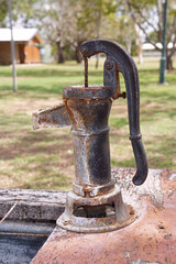 An old rusty hand pump for pumping water into a trough.
