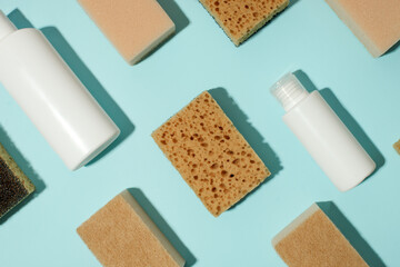 Obraz na płótnie Canvas Set of neutral beige clean sponges, bottles with liquid soap or disinfect on blue background. Banner for site, concept for laundry, cleaning service, advertising, spring regular cleaning day