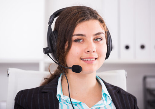 Young female dispatcher is working at a computer and talking headset in the office.