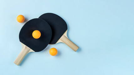 Two black ping pong paddles on light blue background - obrazy, fototapety, plakaty