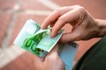 A man counts a stack of euro bills, close up
