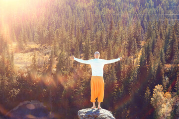 buddhism meditation travel, man doing yoga in traditional yellow pants in nature
