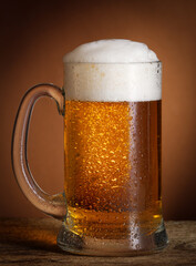 Mug of cold light beer on wooden desk