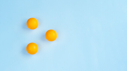 Three ping pong balls on blue background. Image with copy space