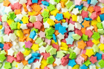 Fototapeta na wymiar Sprinkle sugar stars. Confectionery sweet sprinkles in shape of star. Festive multicolored background.