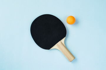 One ping pong paddle and ball on blue background