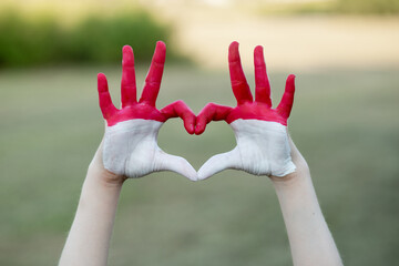 Kid hands in heart form painted in flag Monaco or Indonesia. Tourist made gesture by indonesia flag colored hands showing symbol of heart and love. Indonesian Independence Day, Hari Kemerdekaan