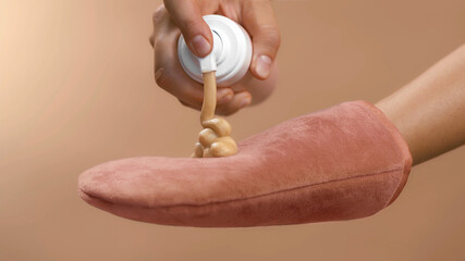 Dosing bronzing lotion or tanning cream from a flask with a doser to a pink tan applicator glove....