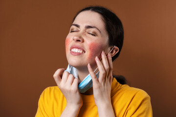 Rosacea. A young upset woman nervously scratches her face with her hands from irritation while...