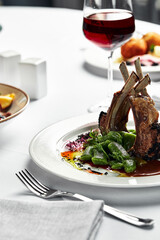 Grilled rack of lamb on a white plate with stewed bean pods. Restaurant serving rack of lamb from the chef.