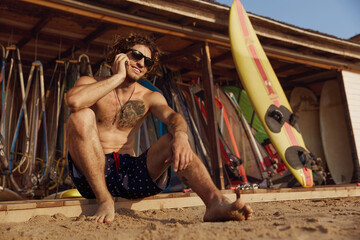 Surfer talking on mobile phone on wooden platform