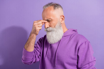 Obraz premium Portrait of attractive depressed elderly grey-haired man touching nose feeling bad isolated over purple violet color background