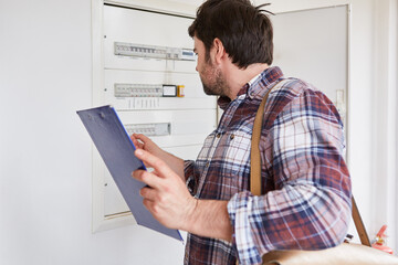 Electrician with checklist on the distribution box