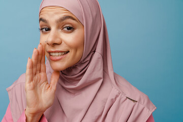 Young muslim woman in hijab gesturing while whispering