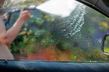 hand wash the hood of the car on a sunny day in the garden after a flood,