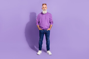 Full length body size view of attractive cheerful grey-haired man hipster holding hands in pockets isolated over purple violet color background